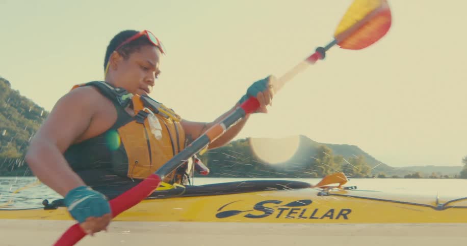 A woman is traveling on a kayak on a sunny day