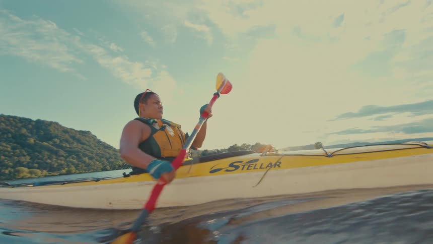 A woman is kayaking in the water on a cloudy day