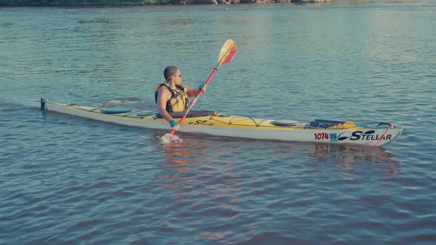 Person paddling a yellow kayak on calm waters