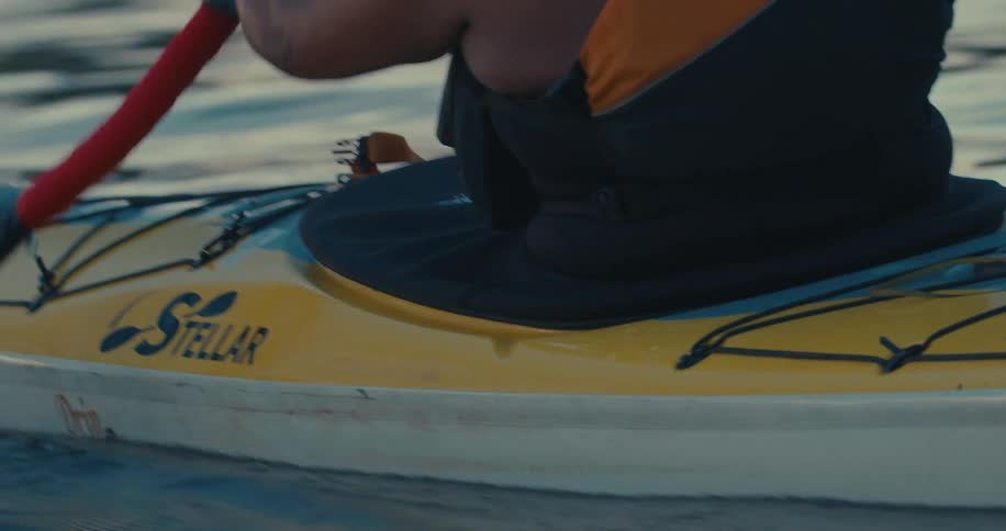 A man rows his kayak over smooth water