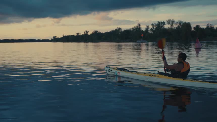 Person performing canoeing on a river in a dark dawn