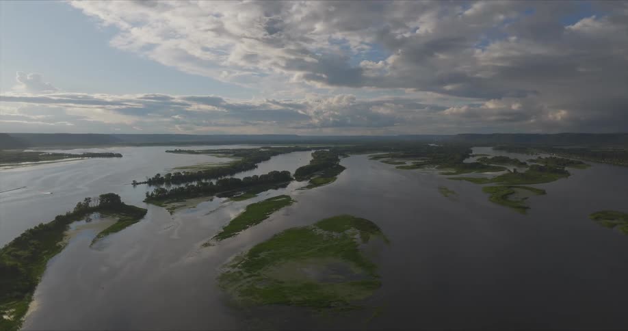 A wide river snakes through a vast landscape dotted with islands and lush vegetation