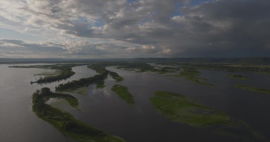 An aerial view of a river with multiple winding channels and green islands under a partly cloudy sky