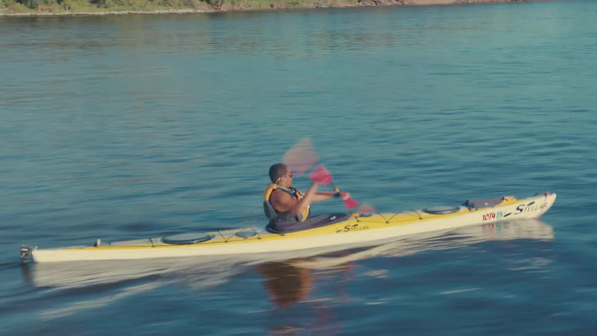 Person canoeing on a river during the day