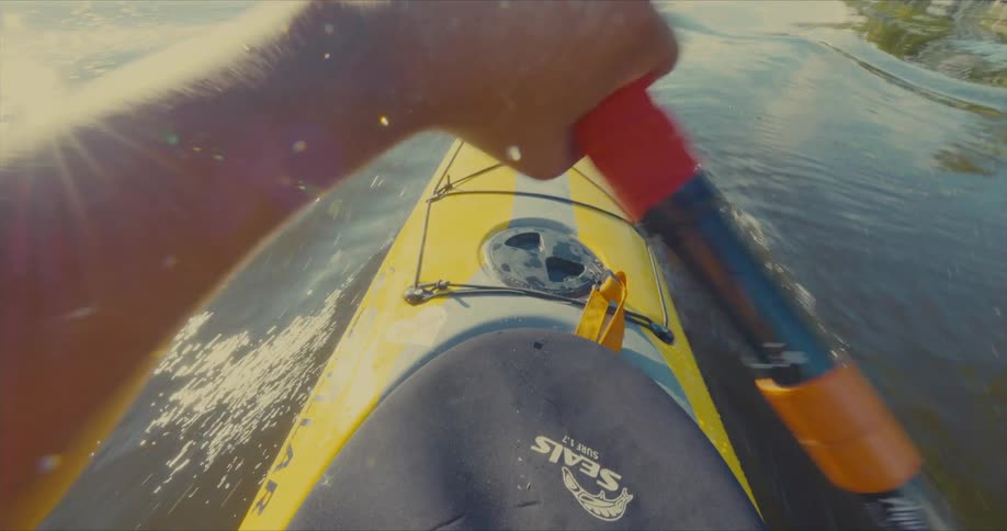 A person is kayaking on a calm body of water using a doublebladed paddle to propel a yellow kayak forward