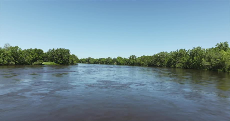 Landscape of a river surrounded by vegetation and a clear blue sky