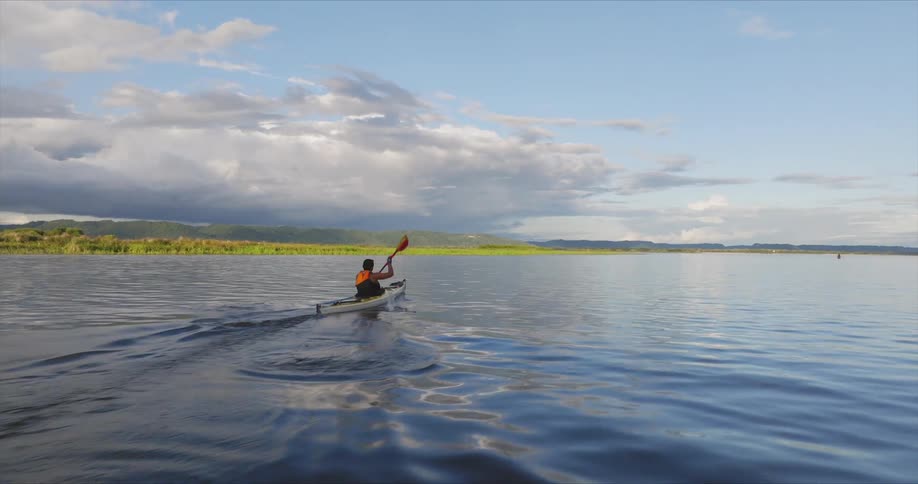 A woman in a canoe rows forward very quickly in a lake