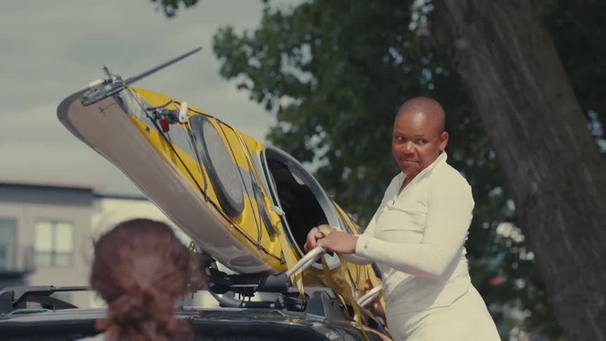 Woman tying a canoe boat to the top of the car