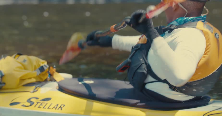 Person wearing a life vest paddles a kayak through the water during the daytime