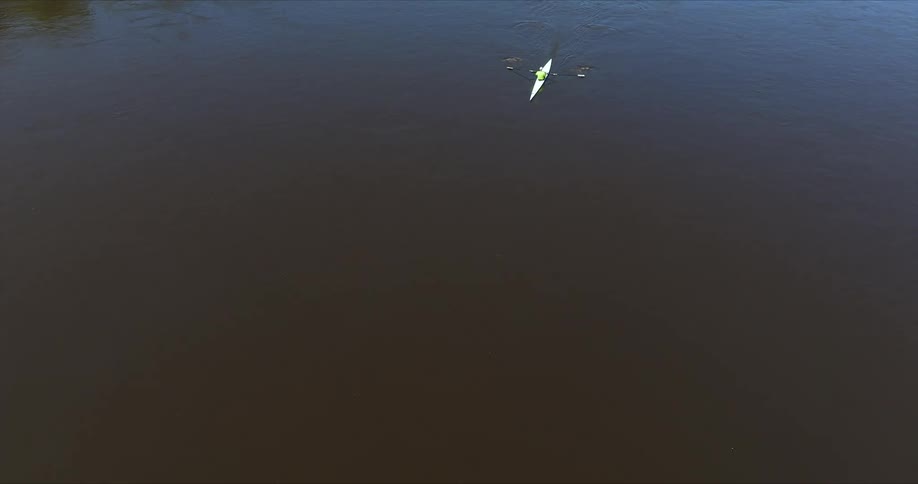 Aerial view of a lone kayak gliding through dark serene waters