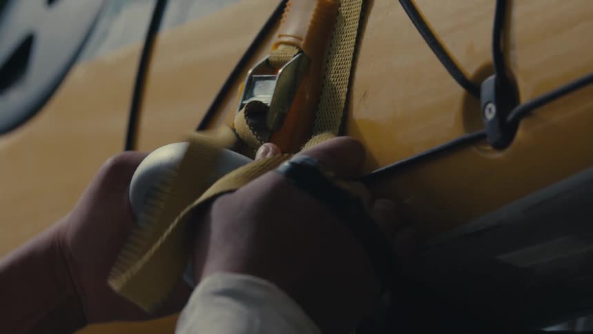 Pair of hands tying a strap to a kayak