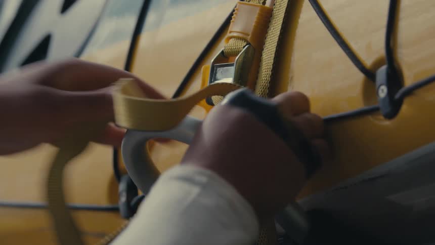 Person with tape across their knuckles uses a strap to attach an object with a u handle