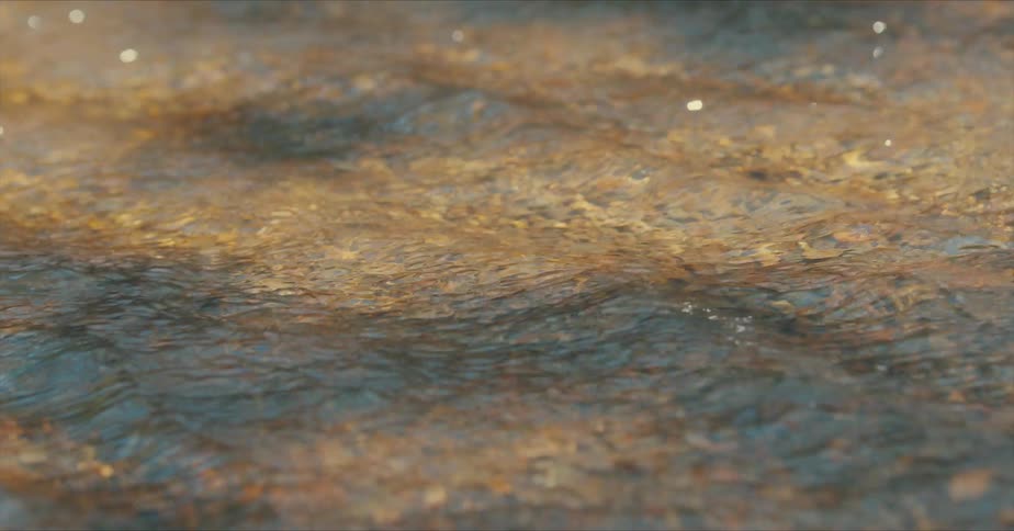 Closeup view of a shallow stream with clear water flowing over a rocky bed