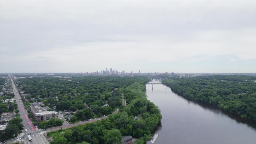 A river winds its way through a cityscape with dense green foliage lining its banks