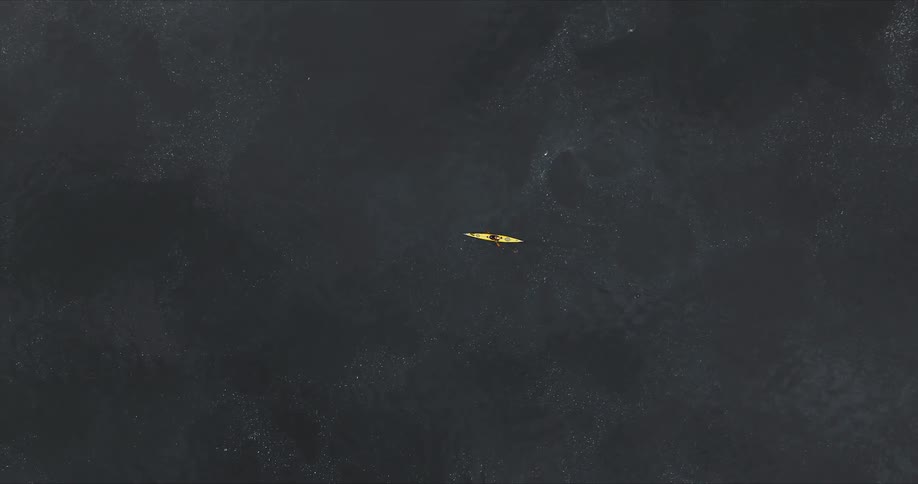 Aerial of a person paddling a kayak across the water during the daytime