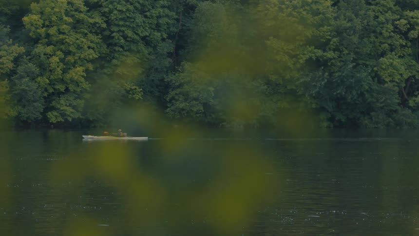 Person canoeing alone on a river surrounded by vegetation