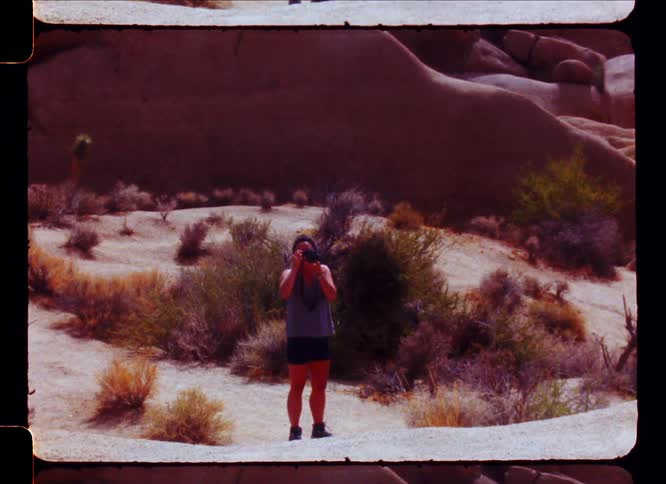 A man lifts his camera to take a photograph in the desert