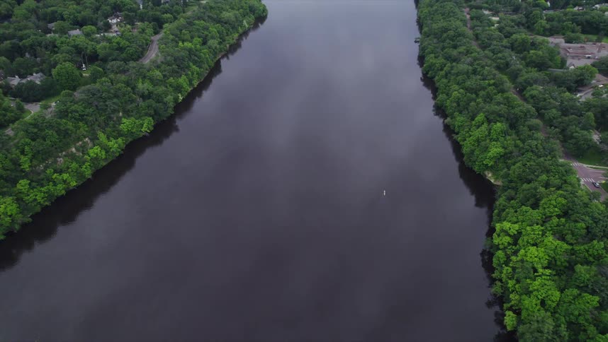 Aerial view of a sea channel surrounded by vegetation and buildings on the horizon