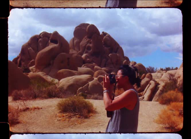 Woman with a camera taking pictures in a natural environment with smoky rocks