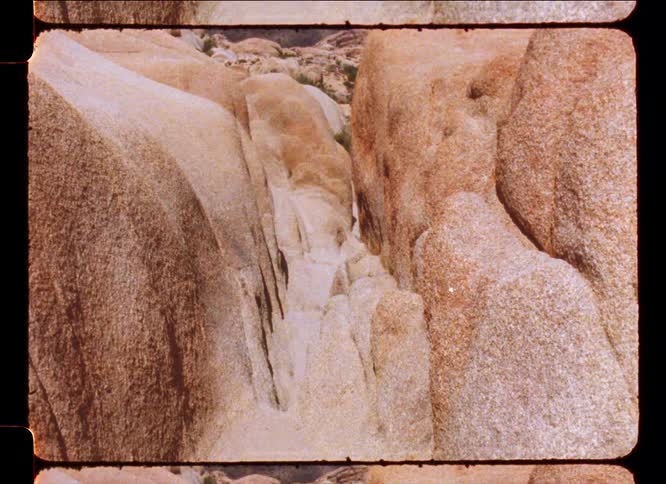 A narrow passage winds its way between towering weathered rocks in a desert landscape