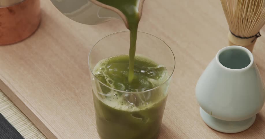 Person pours green tea over the ice in a glass