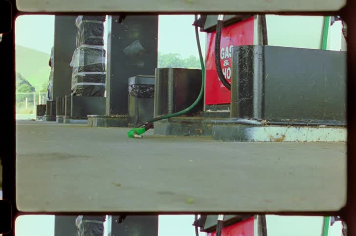 A fuel hose with a green nozzle lying on the ground