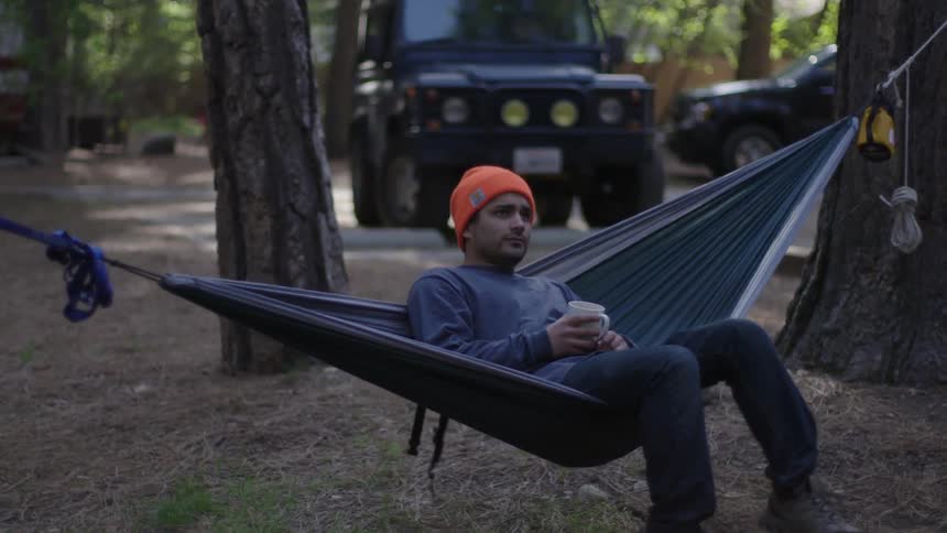 Man sits down on hammock in the woods