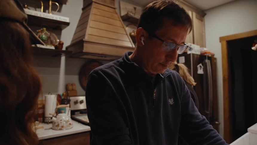Father rolls out cookie dough while the family gathers in the kitchen
