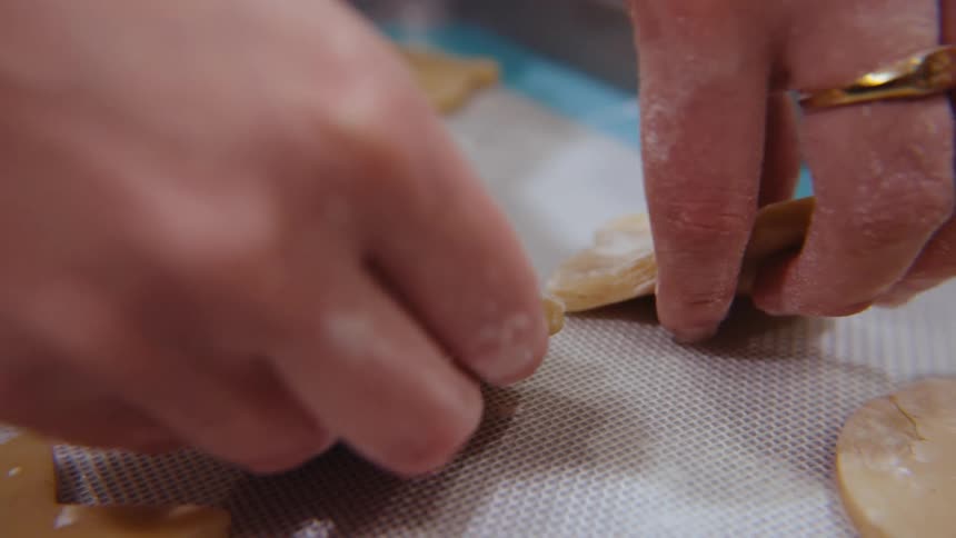 Close up of hands placing cookies on a baking mat