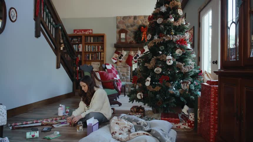 A woman sits on the floor wrapping a christmas gift