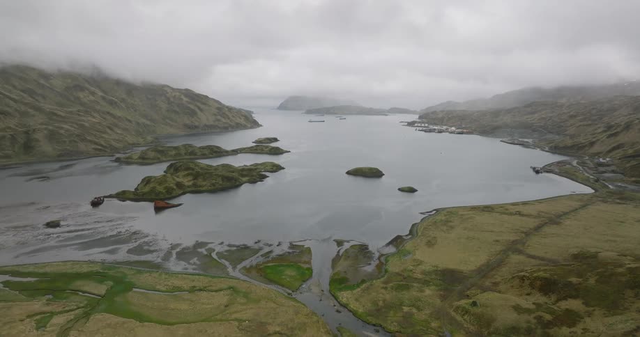 Aerial landscape of sea surrounded by green mountains on a foggy day