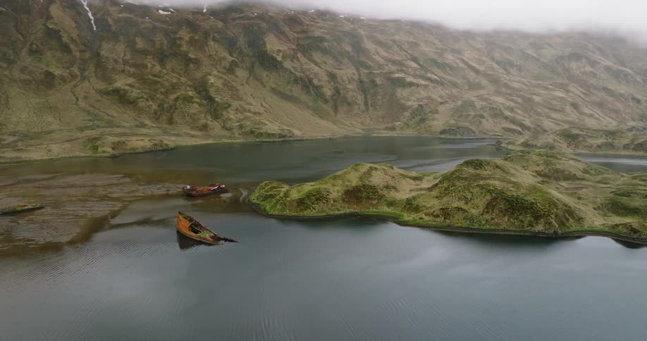 A lake surrounded by green hills with a small island and two boats in the middle