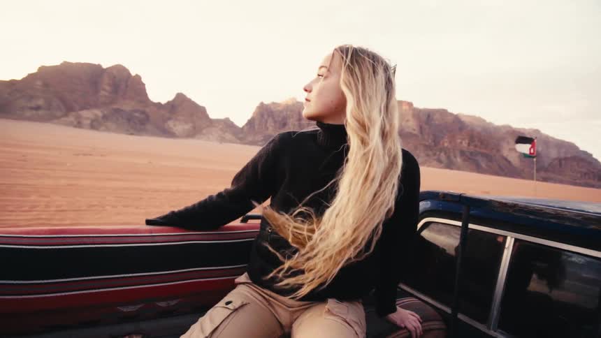 A woman is riding in back of a pickup truck