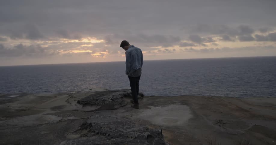 A man stands on a beach on an overcast day