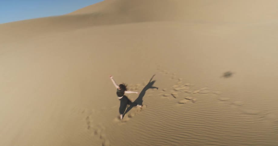 Woman in black dancing in desert dunes