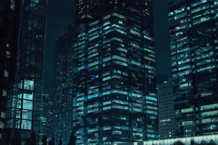 Some large buildings with several apartments with lights turning on as the day dawns