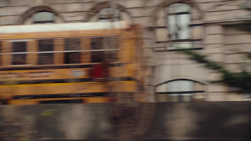 Buses sit on a road paralleling a highway passing through town on an autumn day