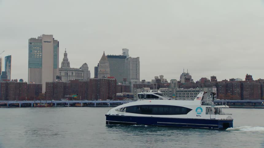 Ferryboat moves down the river toward the brooklyn bridge on an overcast autumn day