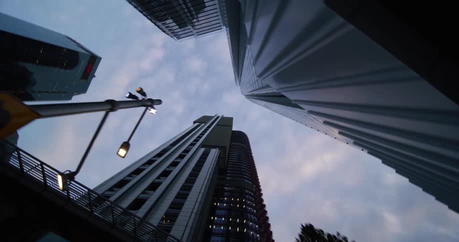 Upward view of modern skyscrapers against a block sky with shades of blue and purple