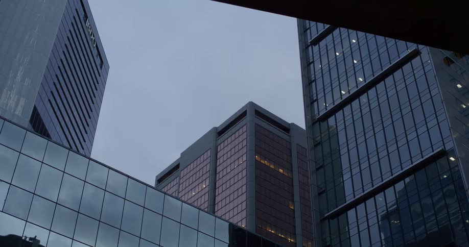 A lowangle view of a towering cityscape with gleaming skyscrapers reaching towards a cloudy sky