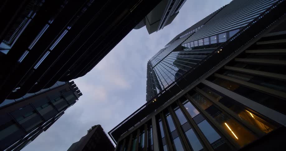 A group of modern skyscrapers with reflective glass facades set against a cloudy overcast sky
