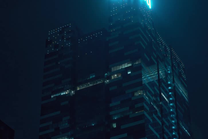 Looking up at a modern office building seen at night with the lights going out