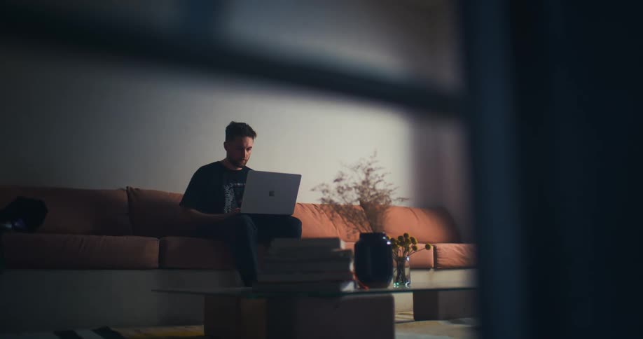 Man sitting on a sofa typing on a laptop