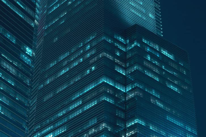Nighttime view of modern office buildings with numerous illuminated windows