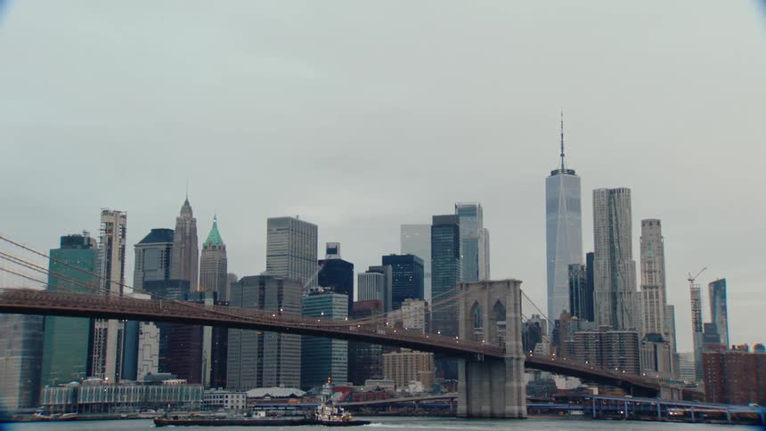 A large ships travels under the bridge in the city
