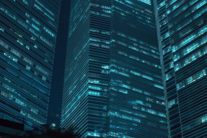 Three modern buildings with lights flashing at night