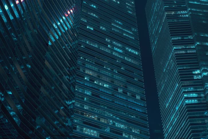 Nighttime view of modern office buildings with numerous illuminated windows flashing