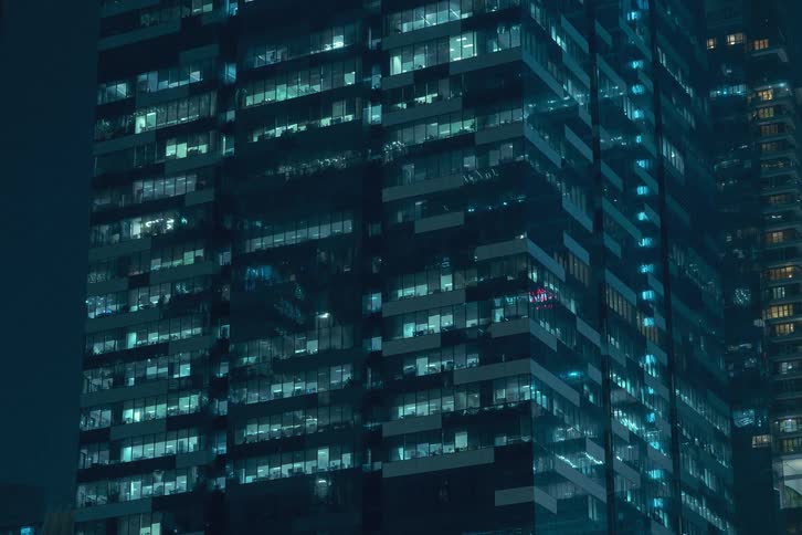 A time lapse of the lights in an office building pulsing and flickering during the night
