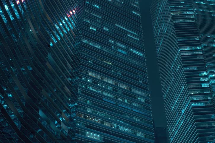 Nighttime view of modern office buildings with numerous illuminated windows flickering
