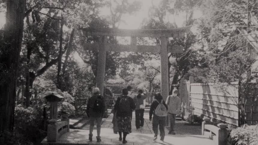People walk on a sidewalk under an arch on a spring day